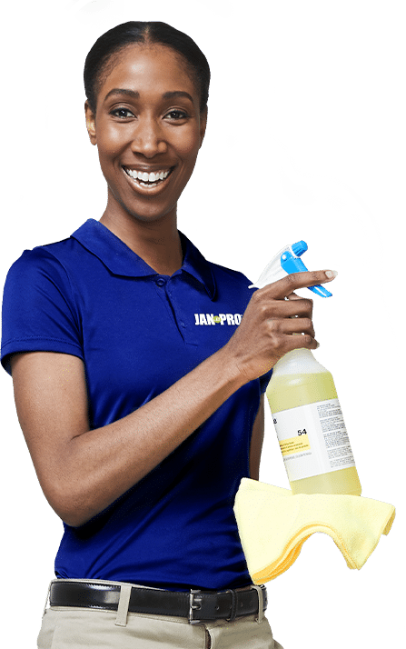 An African-American JAN-PRO Cleaning & Disinfecting employee smiling holding a yellow cloth and spray bottle