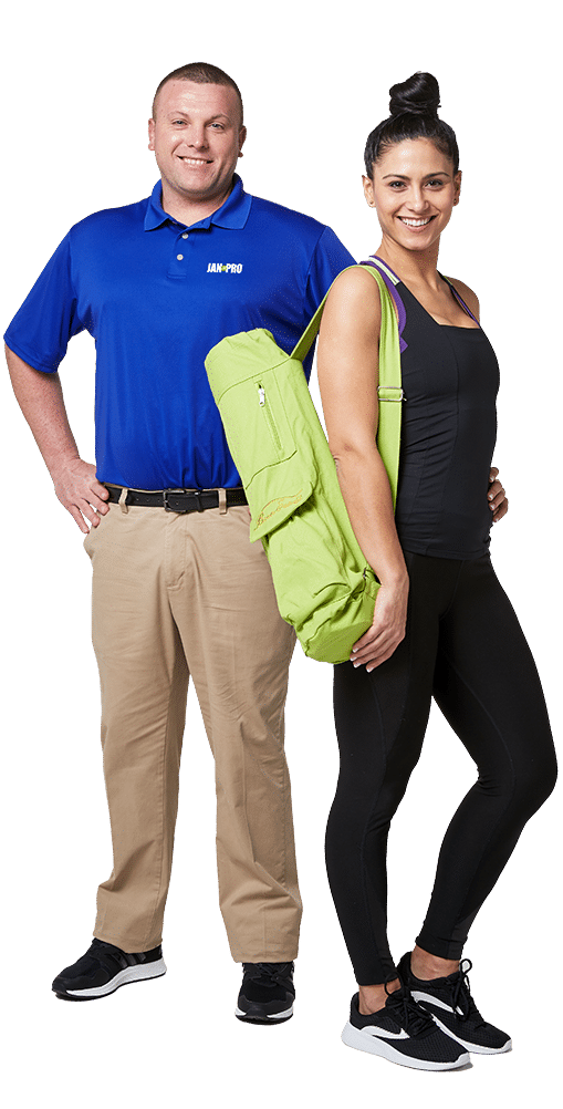 A Caucasian JAN-PRO Cleaning & Disinfecting employee posing with a woman in yoga attire smiling