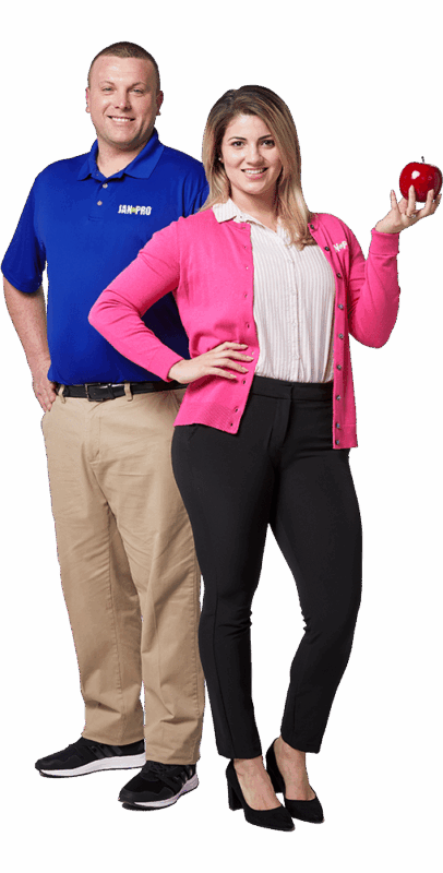 a Caucasian man in JPSI attire and woman teacher holding and apple