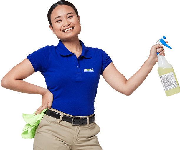 a woman smiling in JAN-PRO Cleaning & Disinfecting attire holding a bright green cloth and spray bottle