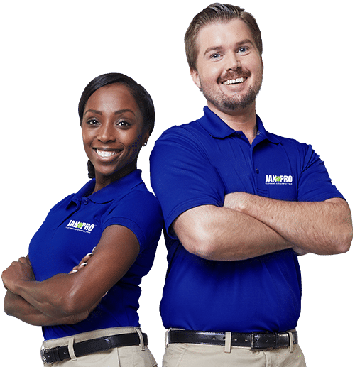 an African-American woman and Caucasian man JAN-PRO Cleaning & Disinfecting attire smiling with their arms folded