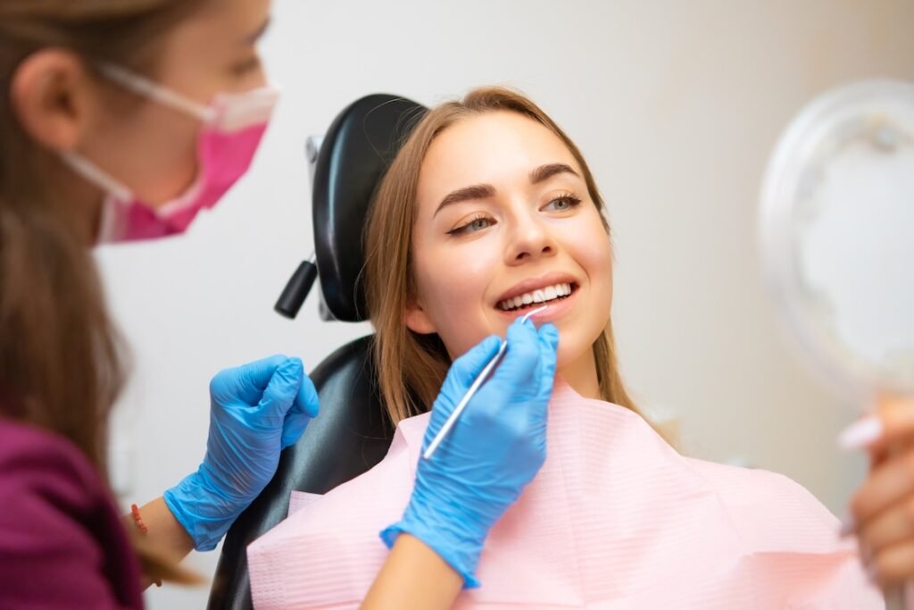 Woman patient sitting in armchair during dental treatment in dental clinic. Doctor checking front teeth with instrument to check soundness of teeth.