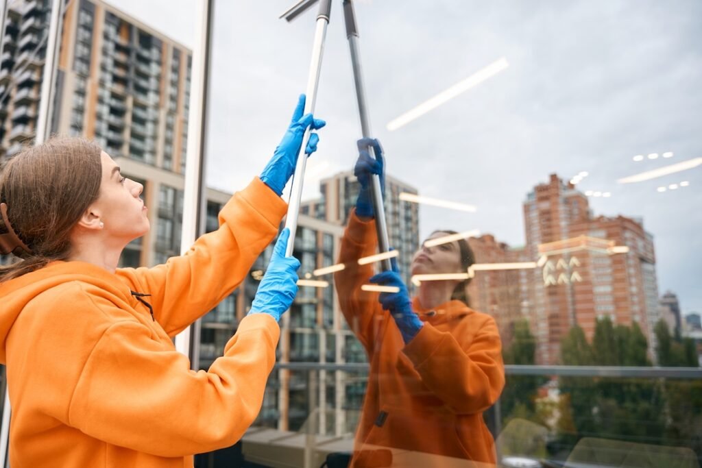 Woman cleaning a window of a commercial building.