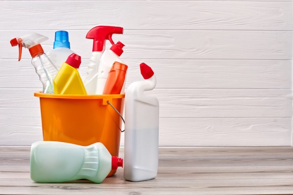 Bucket with cleaning supplies. Cleaning supplies kit on wooden background.