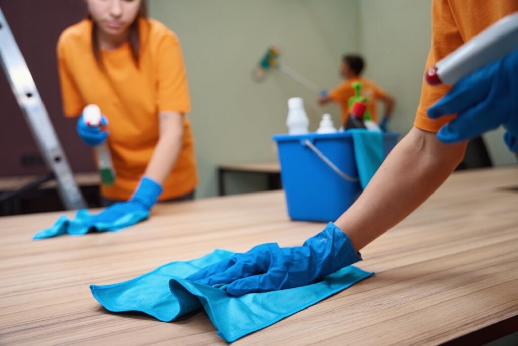 Committed janitor cleaning and sanitizing the table surface