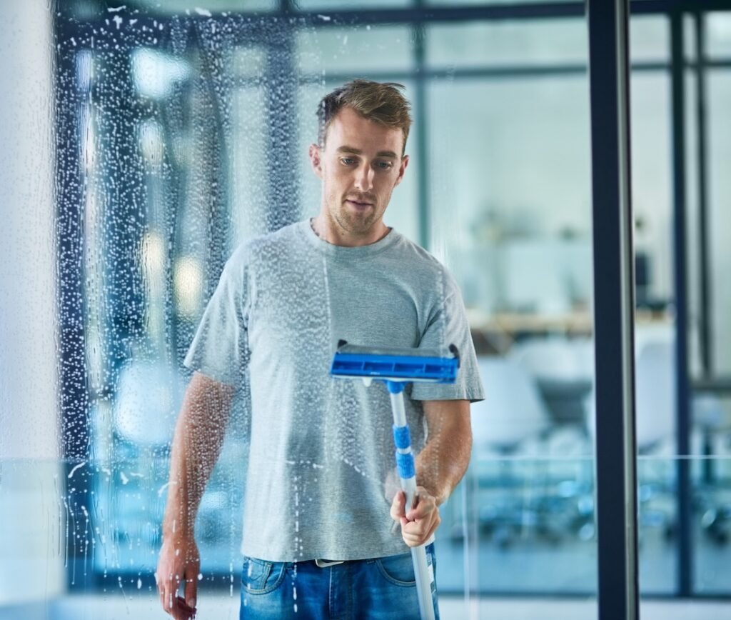 Commercial cleaner wiping down a window.